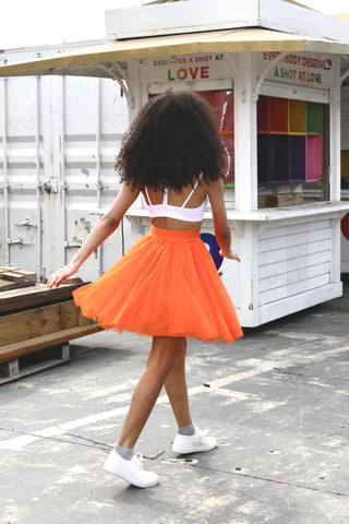 Pretty girl wearing a bright orange short tulle skirt